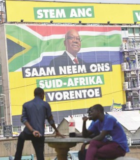 Young people sit in a park in Johannesburg yesterday in front of a billboard calling on the people of South Africa to vote for the ANC in the upcoming election and displaying a portrait of Jacob Zuma. Jacob Zuma yesterday announced that South Africa will hold a general election on May 7. — AFP