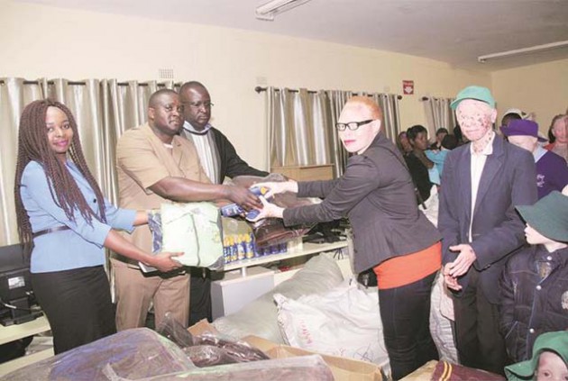 Zimbabwe Amalgamated Housing Association director Dr Killer Zivhu (second from left), ZAHA operations director Mr Phillip Chafunga (third from left) and ZAHA Finance Director Rufaro Ngadze (left) hand over sunscreen, blankets and clothes to Tapiwa Marunge of Alive Albinism Initiative organisation and Gibson Gurumani of Save the Need House representing people living with albinism in Harare yesterday. — (Picture by Memory Mangombe)