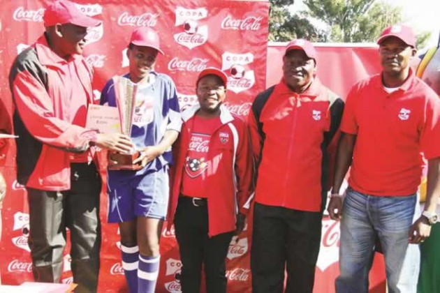 SILVER MEDALLISTS . . . Coca-Cola Angola operations marketing manager Jeremias de Freitas (left) hands over the trophy and cheque to a representative of the Copa Coca-Cola girls’ tournament losing finalists, St Francis Mashonaland Central, while former Warriors skipper and coach Norman Mapeza (left) and Zifa board member John Phiri share the podium at Gwanzura on Sunday