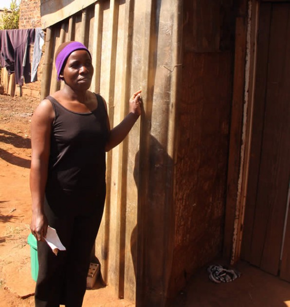 Farness Maliro stands next to the corner partitioned for her father by a Good Samaritan