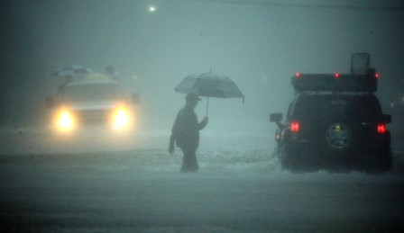A man walks through floodwaters from Tropical Storm Harvey as he evacuates his home