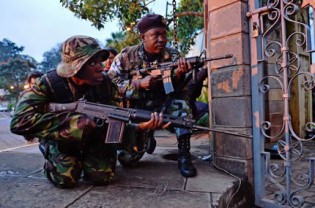 Kenyan soldiers take cover after heavy gunfire was heard at Westgate mall in Nairobi on September 23, 2013. Somali Shebab militants on Monday threatened to kill the hostages they are holding in a Nairobi shopping mall, after massacaring at least 68 people-AFP