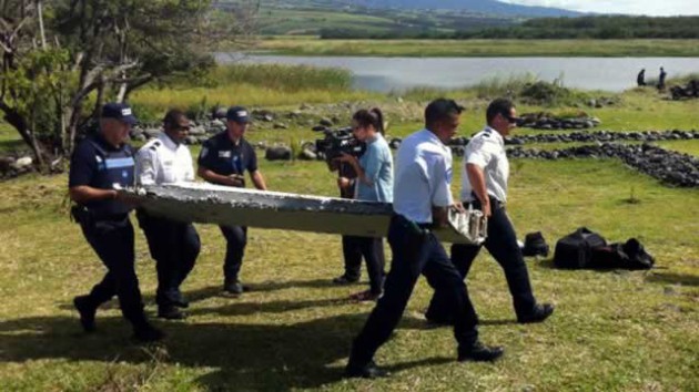 Police carry the Boeing 777 wing part at Reunion Island on July 29, 2015