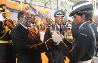 President Mugabe presents a trophy to officer cadet Angeline Bosha who was the overall best student during the pilot pass out parade at Thornhill Airbase in Gweru yesterday, while base commander Group Captain George Ngundu looks on approvingly.