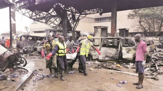 Firefighters carry the charred remains of one of the victims of an explosion at a petrol station in Accra, which killed at least 100 people on Wednesday night