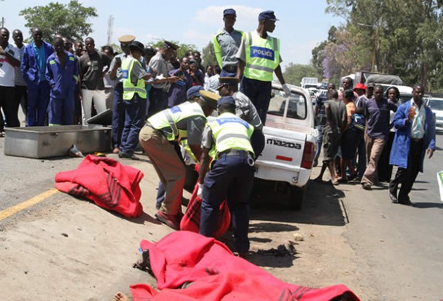 Police officers carry the bodies of the deceased into their vehicle