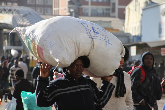 A vendor carries her goods in a sack as the Harare City Council removes illegal vendors today.