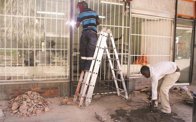 Welders securing a shop whose windows were shattered in the First Street Mall