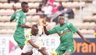 NO WAY THROUGH . . . Zimbabwe midfielder Kuda Mahachi is sent sprawling onto the ground after trying to work his way past two Burkinabe