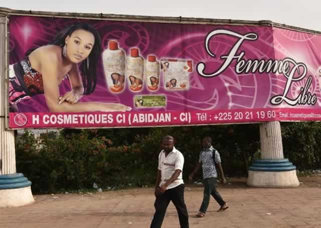 Two men walk past a skin lightening product advert in Ivory Coast recently — AFP