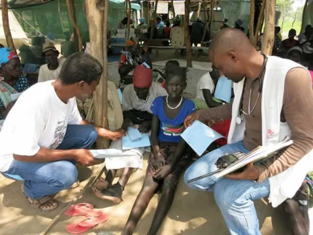 George Mapiye (kneeling left and inset) attends to patients at Lankien village, north east of South Sudan