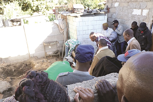 Police Officers collect the late Patience Ncube's body from the shallow pit(left) behind the family house where she was buried.