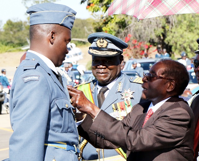 The President and Commander-In- Chief of the Zimbabwe Defence Forces, Cde Mugabe, presents a wing to pilot Campbell Mohadi Junior at the Pilot Wings presentation and commissioning parade of cadets at ThornHill Air Base in Gweru. Looking on is Air Marshal Perence Shiri. — (Picture by Eliah Saushoma)