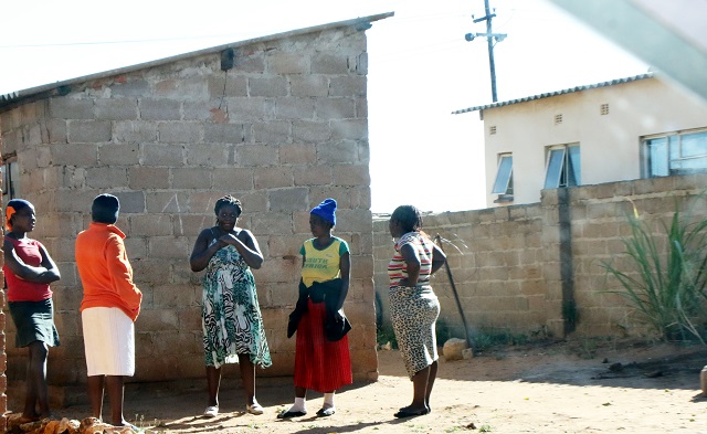 Shocked Pumula residents stand outside the house where a child was murdered and buried in the yard