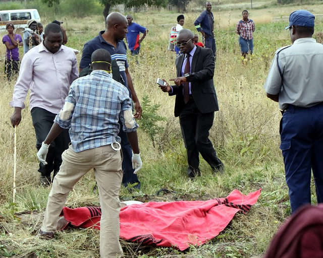 Police officers prepare to collect the body of a woman who was found dead in Pelandaba, Bulawayo