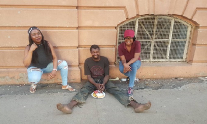 Miss Nicole Mkhethwa (left) and Miss Sithabile Gandi Ndlovu with a homeless man